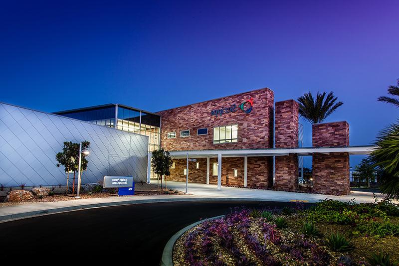 Exterior photo of California Proton Cancer Therapy Center at dusk of entrance drive and landscaping.